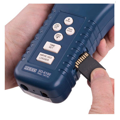 Hand holding a blue REED SD-6100 device with buttons on a white background